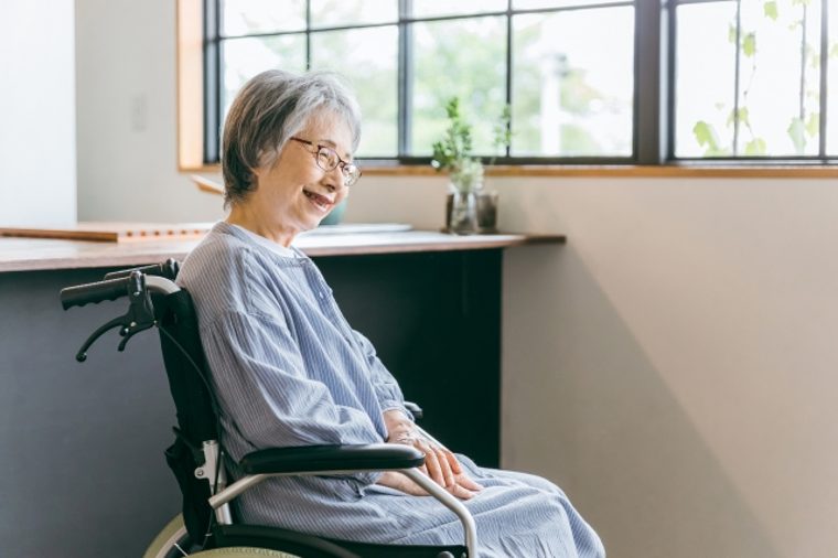 明るい窓辺で笑顔の高齢女性が自宅で過ごす様子